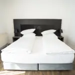 Nahaufnahme des Bettes im Hotelzimmer mit frischer, weißer Bettwäsche