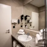 Badezimmer im Hotel mit Waschbecken, Spiegel und Handtüchern