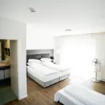Hotelzimmer mit großem Doppelbett und einem Einzelbett, Nachttisch und gemütlicher Beleuchtung