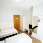 Hotelzimmer mit zwei Einzelbetten, Fenster und minimalistischer Einrichtung